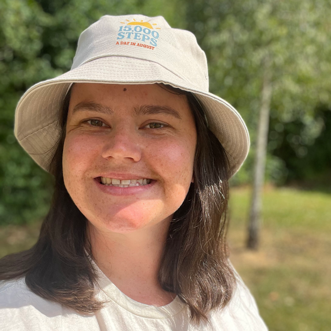a smiley selfie in the steps challenge tshirt wearing a beige bucket hat with 15,000 steps a day in August written on it